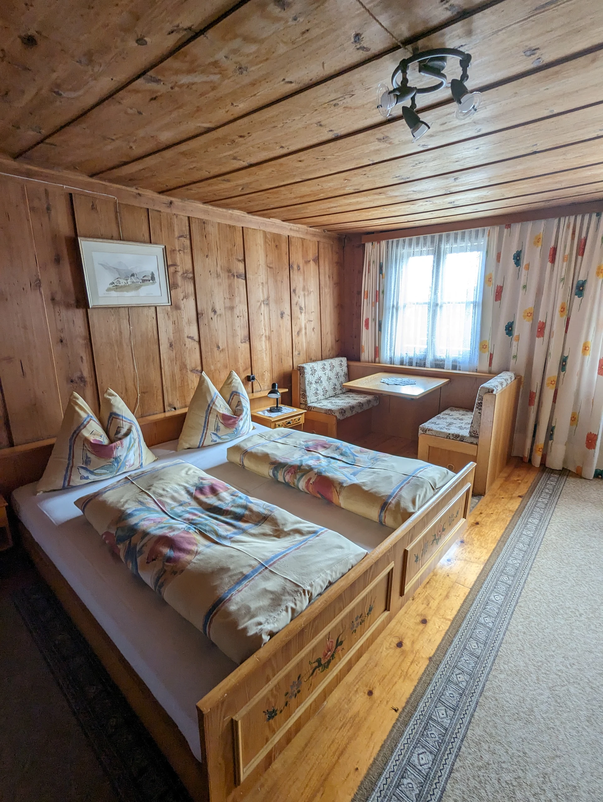 Geräumiges Holzzimmer mit Doppelbett und gemütlicher Sitzecke