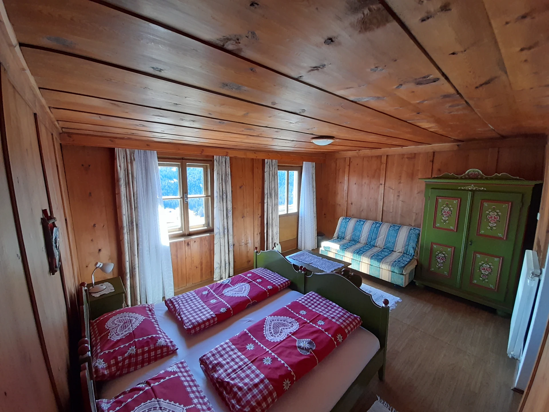 Großzügiges Holzzimmer mit Doppelbett, Sofa und Bauernschrank